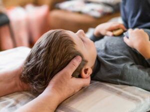 A person gently stretching their back in a sunlit living room with a cozy, rural look.