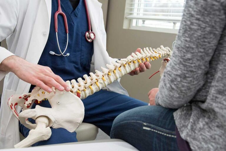 A clinician assesses a seated adult with neck pain radiating toward the shoulder during a musculoskeletal exam.